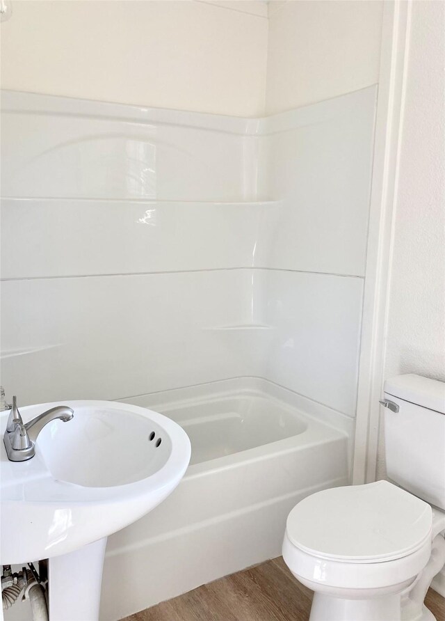 bathroom with wood-type flooring, bathing tub / shower combination, and toilet