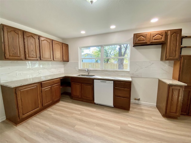 kitchen with light hardwood / wood-style floors, dishwasher, sink, and backsplash