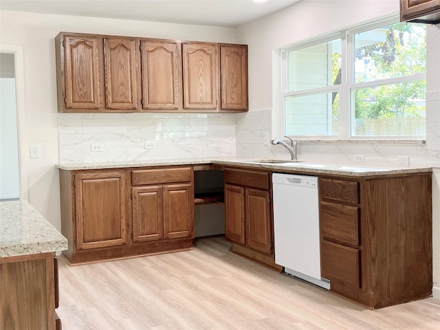 kitchen with sink, light hardwood / wood-style flooring, white dishwasher, light stone countertops, and decorative backsplash