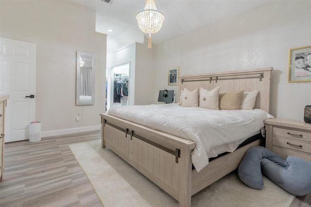 bedroom featuring light wood-type flooring, a spacious closet, a closet, and a notable chandelier