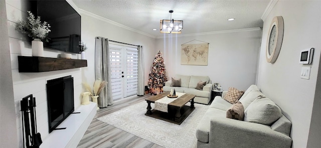 living room with crown molding, light wood-type flooring, a textured ceiling, and a chandelier