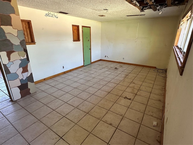 tiled empty room featuring a textured ceiling