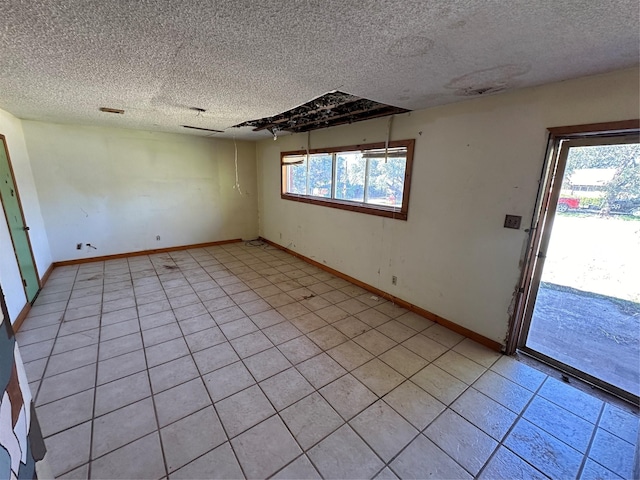 spare room featuring light tile patterned flooring, a textured ceiling, and a wealth of natural light