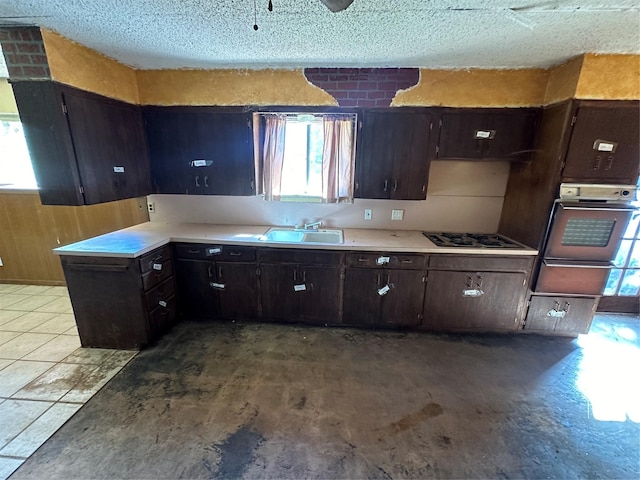 kitchen featuring dark brown cabinetry, sink, and oven