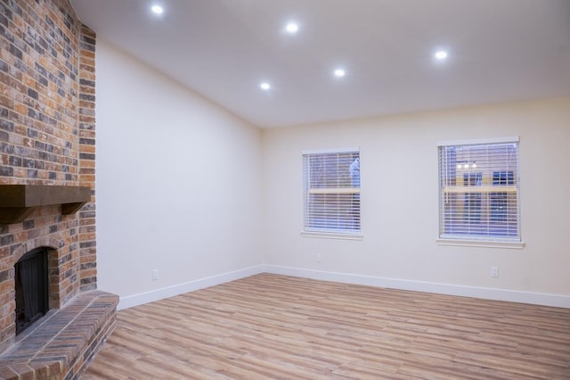 unfurnished living room with a brick fireplace and light hardwood / wood-style flooring