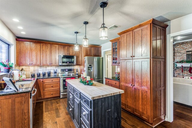 kitchen featuring stainless steel appliances, a center island, dark wood-type flooring, and decorative light fixtures