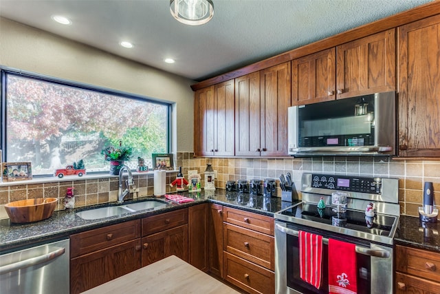 kitchen featuring stainless steel appliances, tasteful backsplash, sink, and dark stone counters