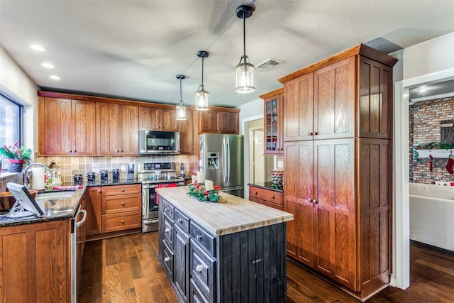 kitchen featuring dark hardwood / wood-style flooring, stainless steel appliances, sink, pendant lighting, and a center island