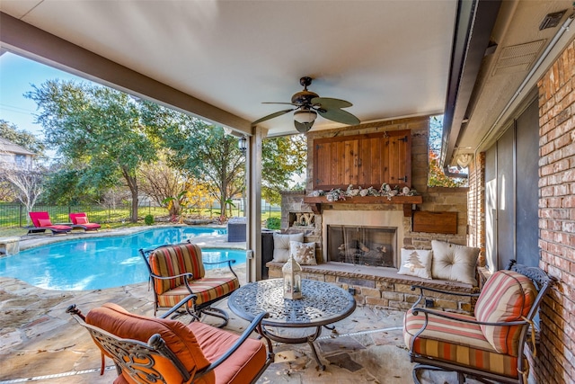 view of patio with a fenced in pool, an outdoor stone fireplace, and ceiling fan