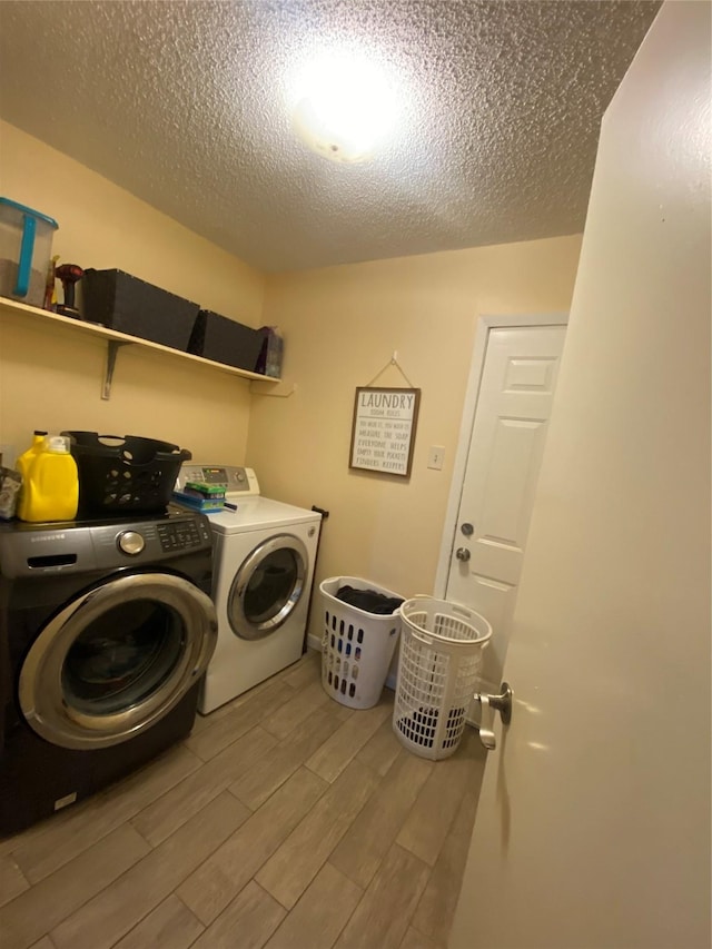 clothes washing area with hardwood / wood-style floors, washing machine and dryer, and a textured ceiling