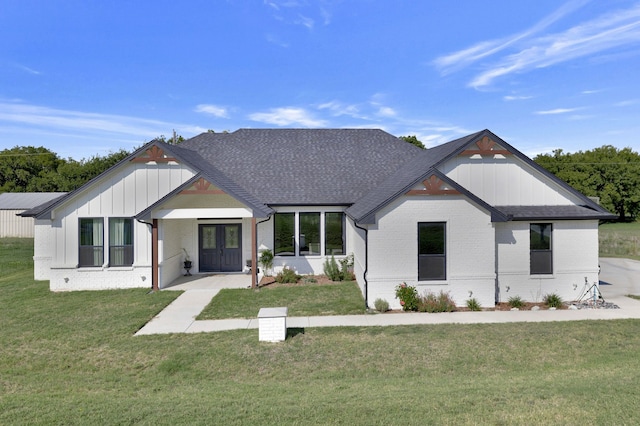 modern farmhouse featuring brick siding, board and batten siding, a front lawn, and roof with shingles