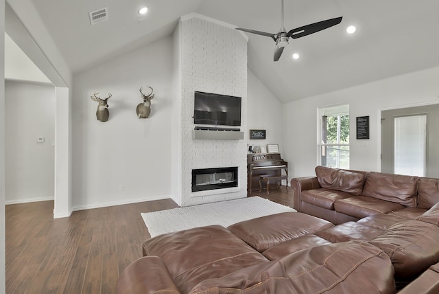 living room featuring a brick fireplace, dark hardwood / wood-style floors, high vaulted ceiling, and ceiling fan