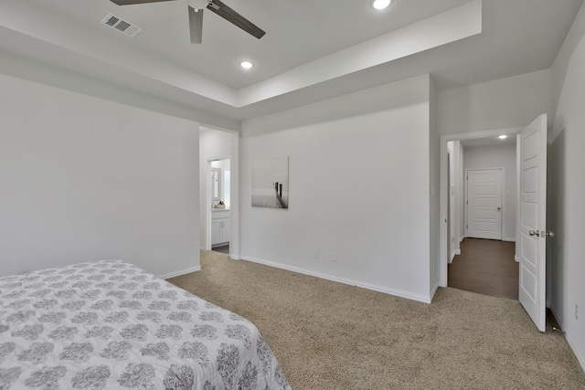 carpeted bedroom with ceiling fan and a tray ceiling