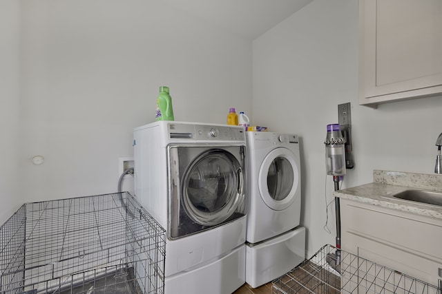 clothes washing area featuring washer and dryer, sink, cabinets, and dark tile patterned floors