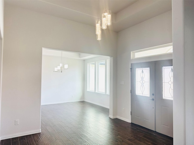 entrance foyer with a notable chandelier, dark wood-type flooring, a raised ceiling, and french doors