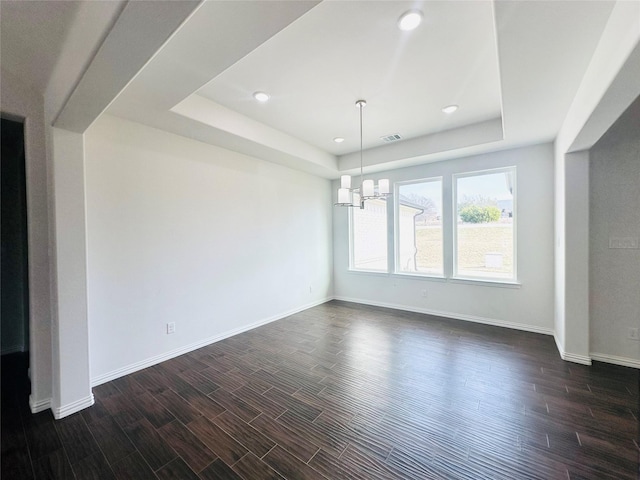 unfurnished dining area featuring a raised ceiling, a chandelier, and dark hardwood / wood-style flooring