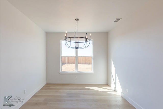 unfurnished dining area with a chandelier and light hardwood / wood-style flooring