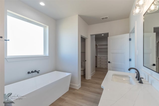 bathroom featuring vanity, hardwood / wood-style floors, a washtub, and toilet