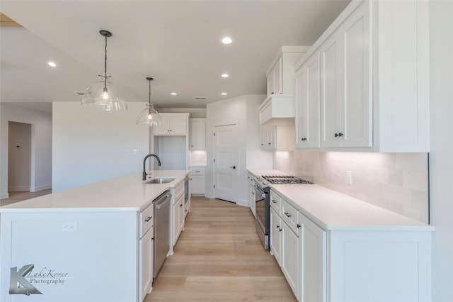 kitchen with sink, white cabinetry, hanging light fixtures, a large island with sink, and appliances with stainless steel finishes