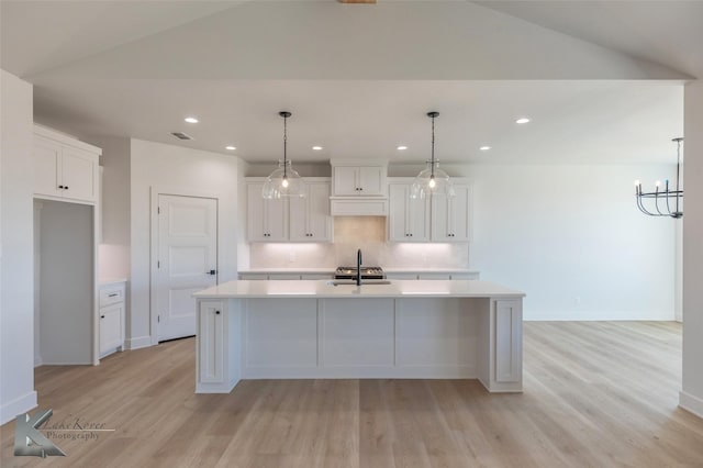 kitchen featuring white cabinetry, an island with sink, hanging light fixtures, and decorative backsplash