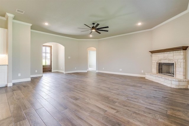 unfurnished living room with a fireplace, light wood-type flooring, ceiling fan, and crown molding