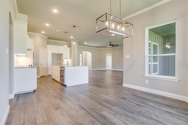 kitchen featuring a center island with sink, white cabinets, ceiling fan, decorative light fixtures, and light hardwood / wood-style floors