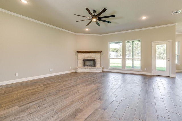 unfurnished living room with ceiling fan, light hardwood / wood-style floors, a stone fireplace, and crown molding