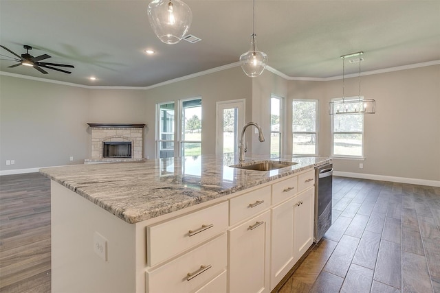 kitchen with white cabinetry, sink, dark wood-type flooring, light stone counters, and a kitchen island with sink