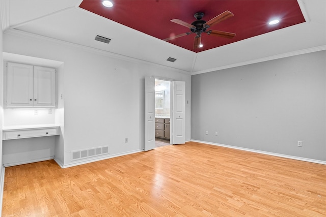 unfurnished bedroom featuring ceiling fan, light wood-type flooring, crown molding, and ensuite bath