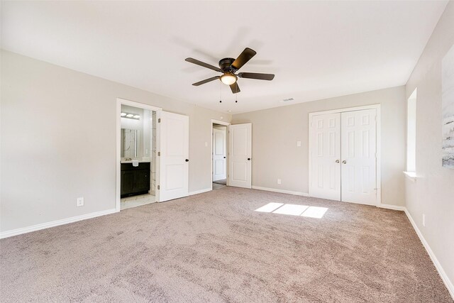 unfurnished bedroom featuring ceiling fan, light colored carpet, ensuite bathroom, and a closet