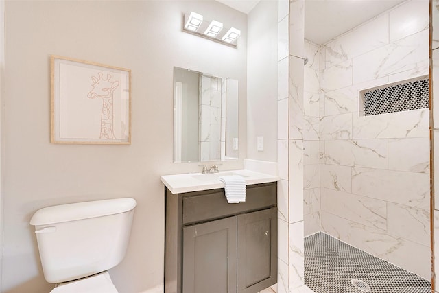 bathroom with vanity, toilet, and a tile shower