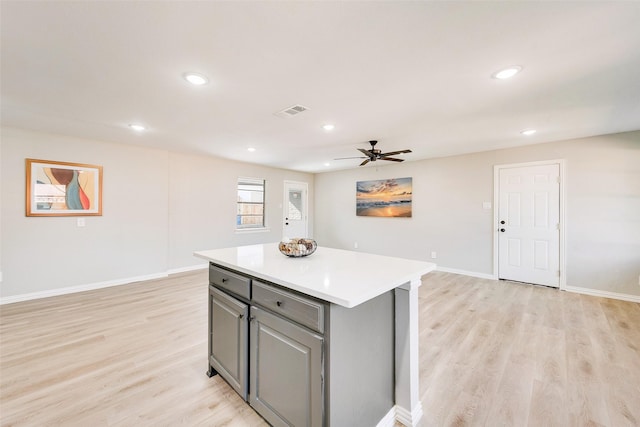 kitchen featuring light hardwood / wood-style flooring, gray cabinets, ceiling fan, and a kitchen island