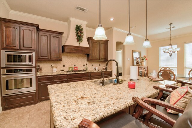 kitchen featuring appliances with stainless steel finishes, sink, a center island with sink, and decorative light fixtures