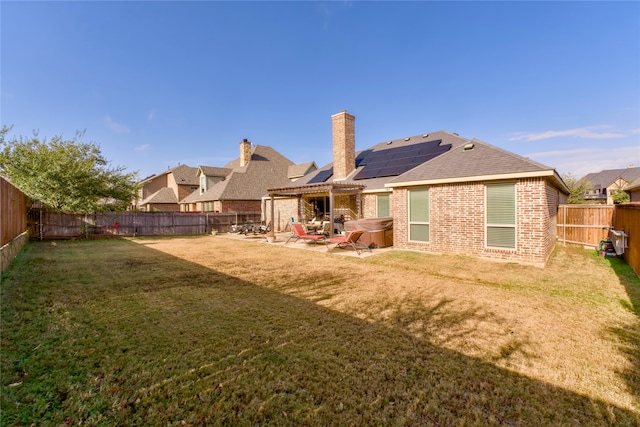 back of property featuring a yard, a patio, and a hot tub