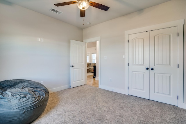 living area featuring light carpet and ceiling fan