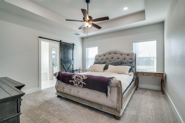 bedroom featuring ceiling fan, a barn door, ensuite bathroom, and light carpet