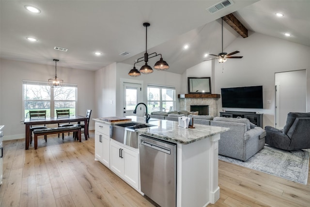 kitchen featuring dishwasher, decorative light fixtures, white cabinetry, and an island with sink