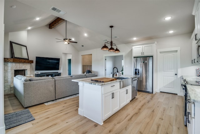 kitchen featuring a center island with sink, white cabinetry, stainless steel appliances, and light hardwood / wood-style floors