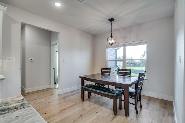 dining room with light hardwood / wood-style flooring and a chandelier