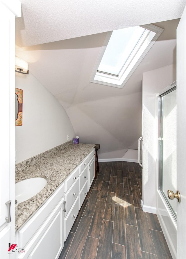 bathroom with vanity, bath / shower combo with glass door, and vaulted ceiling with skylight