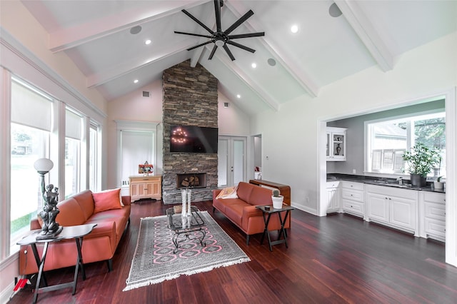 living room featuring a stone fireplace, dark wood-type flooring, high vaulted ceiling, and beamed ceiling