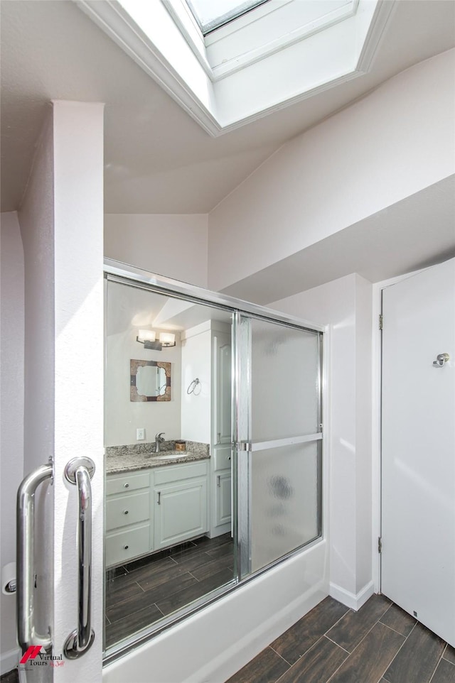 bathroom with vanity, lofted ceiling with skylight, and shower / bath combination with glass door