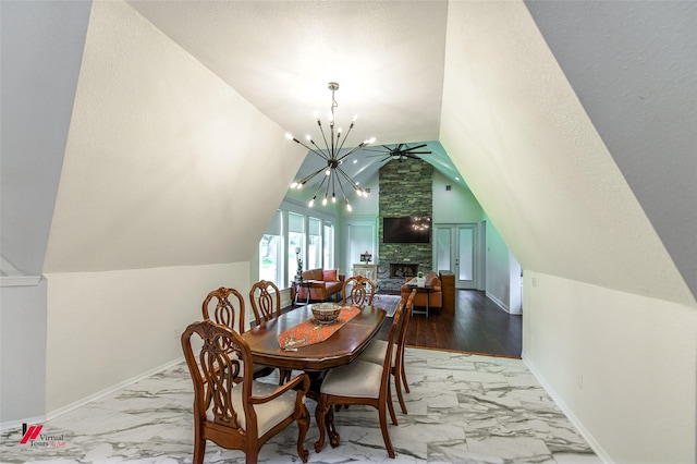 dining room featuring a notable chandelier, a fireplace, and vaulted ceiling