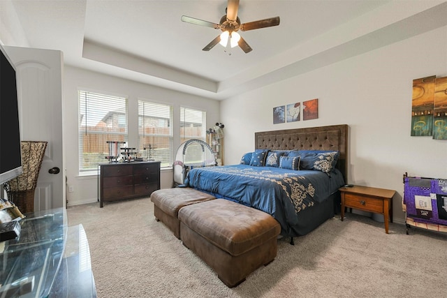 bedroom with light carpet, ceiling fan, and a tray ceiling