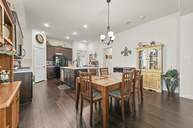 dining room with sink, dark hardwood / wood-style flooring, and an inviting chandelier