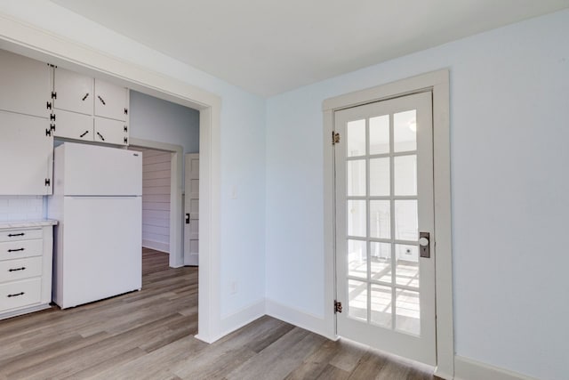 kitchen featuring white refrigerator, light hardwood / wood-style floors, and white cabinets