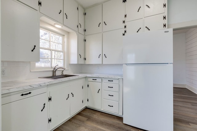 kitchen featuring dark hardwood / wood-style floors, white cabinetry, sink, decorative backsplash, and white fridge