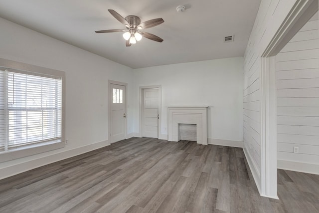 unfurnished living room with hardwood / wood-style flooring, a brick fireplace, a wealth of natural light, and ceiling fan