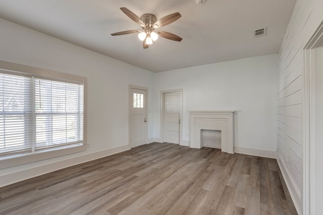 unfurnished living room featuring ceiling fan, a fireplace, and light wood-type flooring