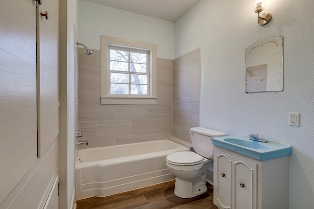 full bathroom featuring vanity, hardwood / wood-style floors, tiled shower / bath combo, and toilet